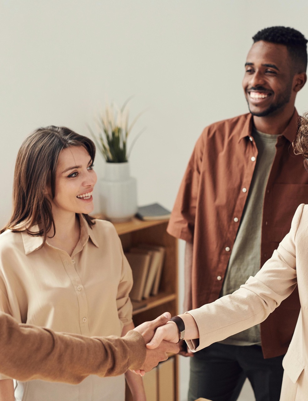 Woman and man in business casual attire smiling while counterparts shake hands