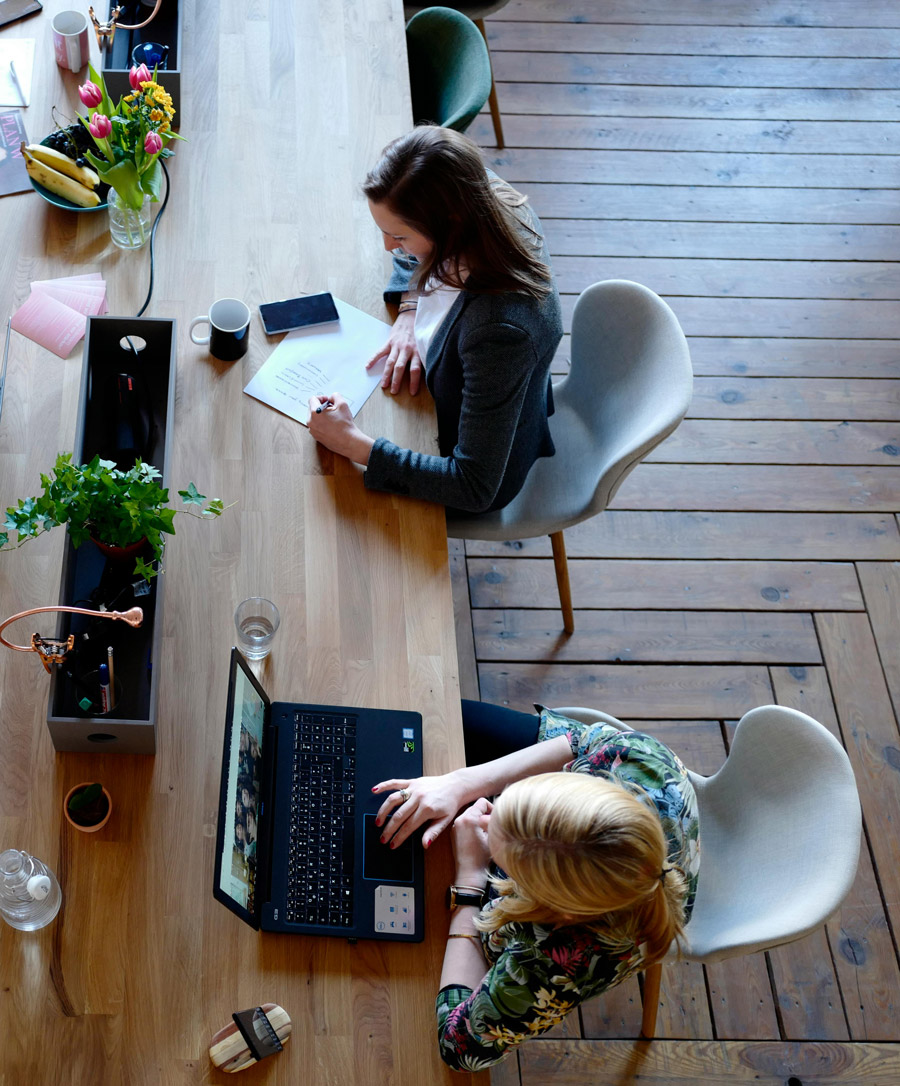 Three Woman Sitting on White Chair in Front of Table