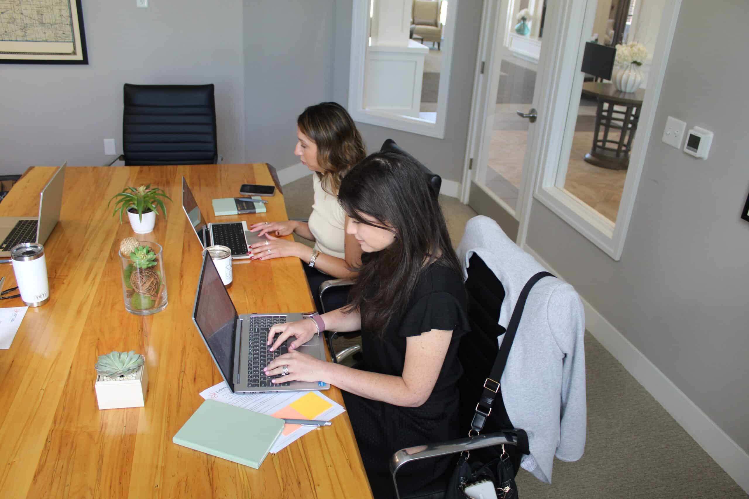Three Woman Sitting on White Chair in Front of Table